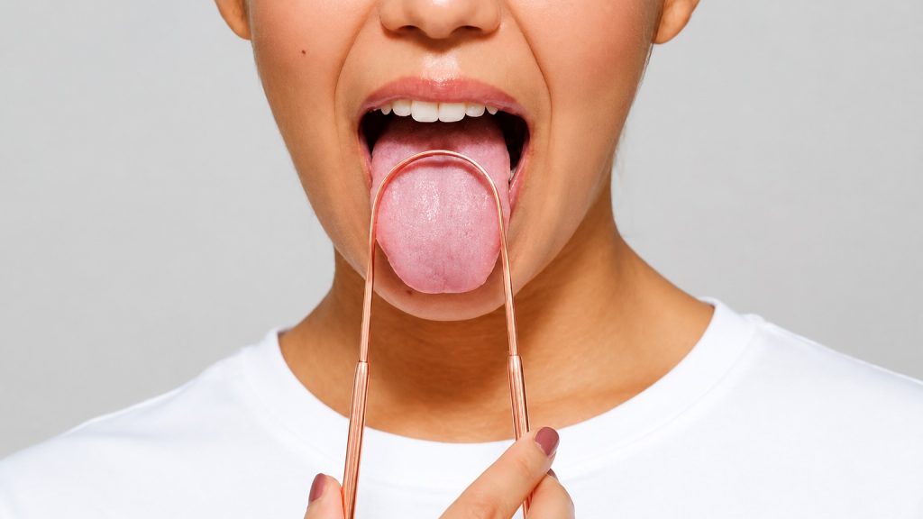 Persona utilizando un raspador lingual para limpiar la lengua