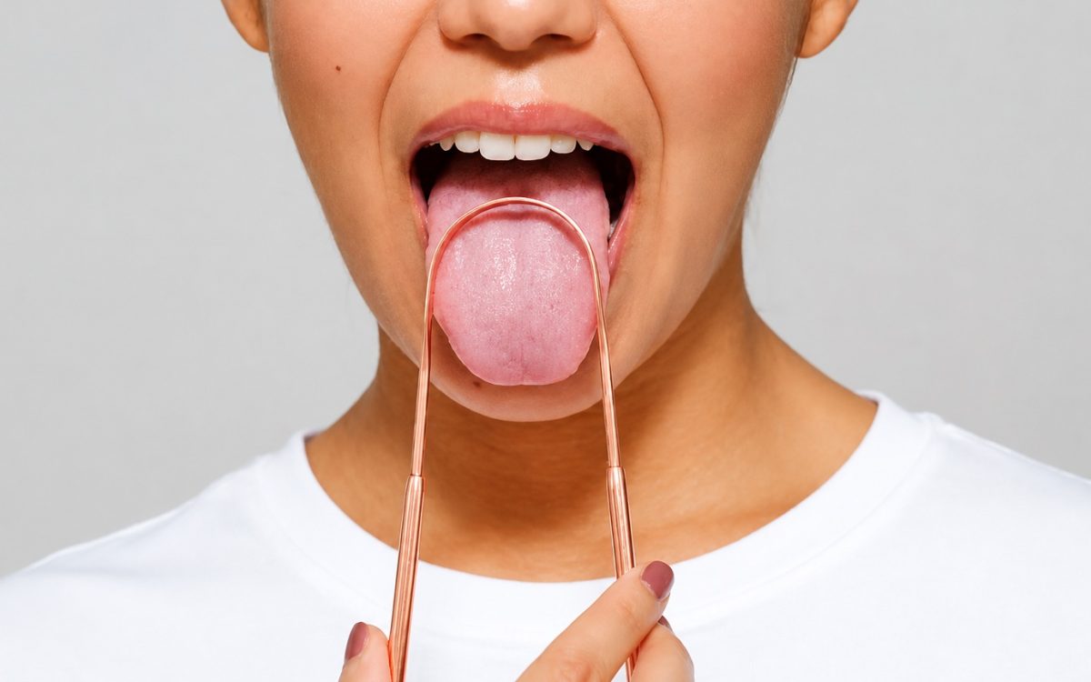 Persona utilizando un raspador lingual para limpiar la lengua